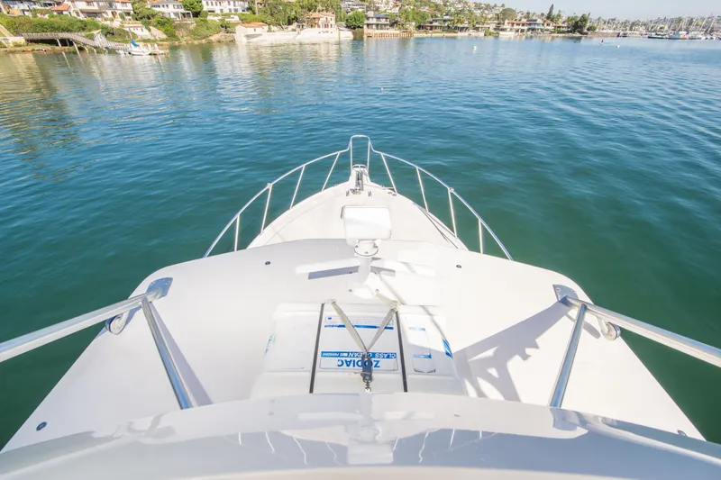 Slide: The Image of Bow view of 2005 Cabo 35 Express yacht on calm waters near coastal homes. - 6