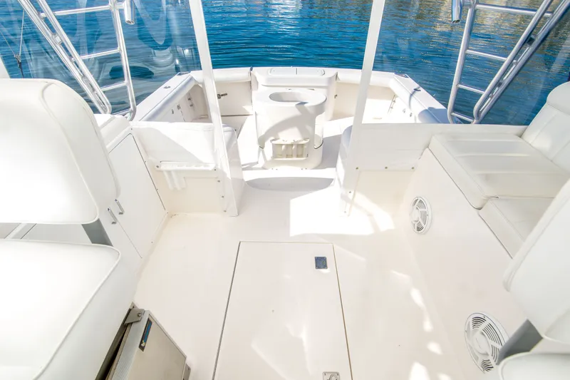 Slide: The Image of 2005 Cabo 35 Express boat interior with white seating and open deck, docked on calm water. - 15