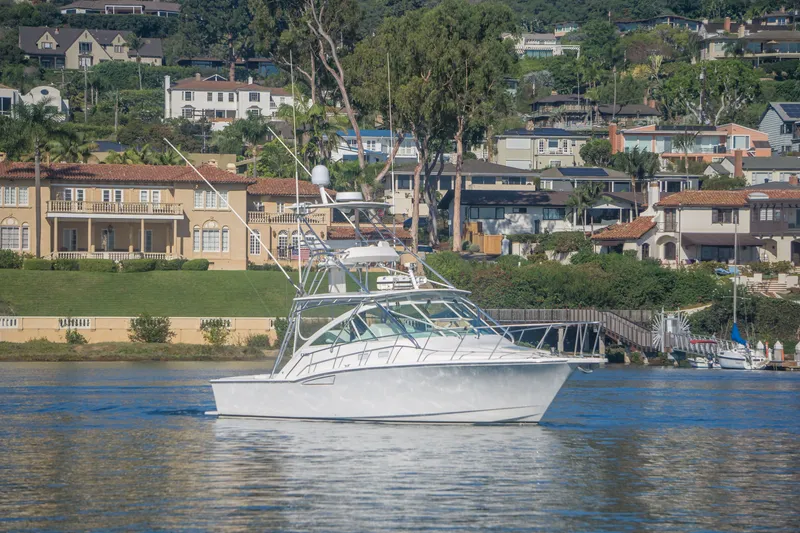 Slide: The Image of 2005 Cabo 35 Express boat cruising near luxurious waterfront homes. - 1