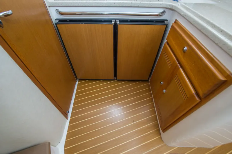 Slide: The Image of 2005 Cabo 35 Express interior with wooden cabinets and striped flooring. - 29
