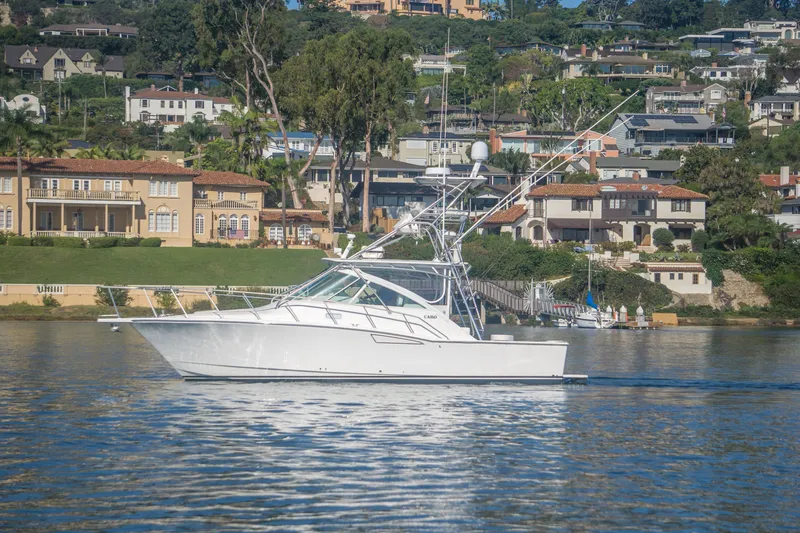Slide: The Image of 2005 Cabo 35 Express yacht cruising near luxurious waterfront homes. - 3