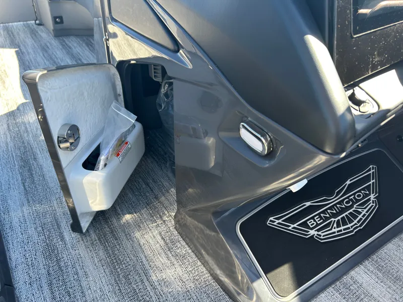 Slide: The Image of The image shows the interior of a Bennington 27QXSB boat with gray carpeting and an open storage compartment. - 25