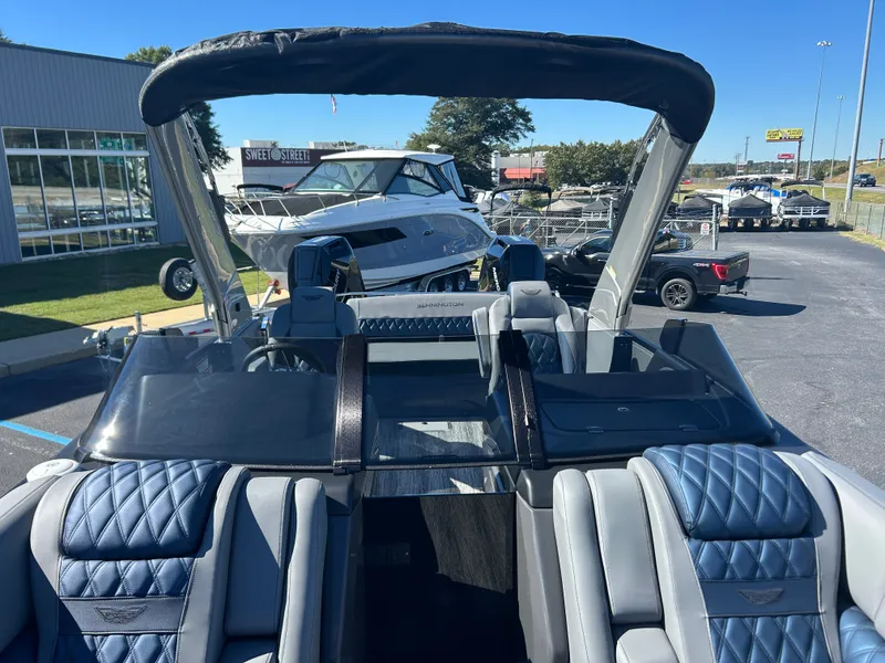 Slide: The Image of A luxurious Bennington boat with blue and gray seats, parked in an outdoor showroom. - 29