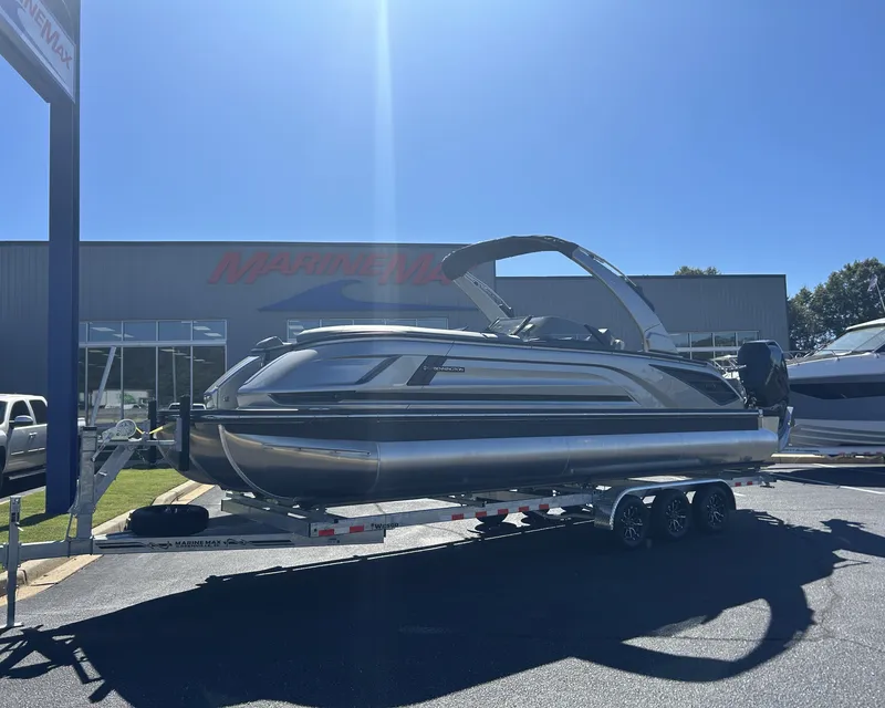 Slide: The Image of A sleek 2027 Bennington 27QXSB pontoon boat sits on a trailer in front of a building. - 1