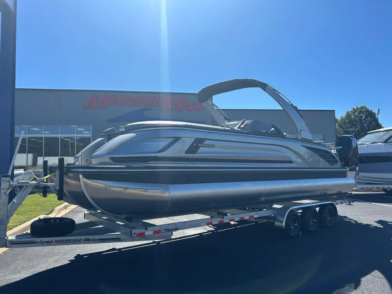 Slide: The Image of A sleek 2027 Bennington 27QXSB pontoon boat on a trailer in front of a building. - 2