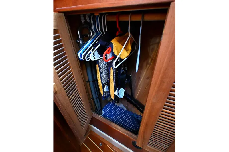 Slide: The Image of Wooden closet with hangers and clothes inside a 2002 Island Packet 350 sailboat. - 42