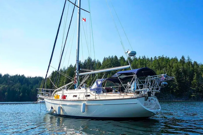 The Image of 2002 Island Packet 350 sailboat anchored in scenic forested bay. - 0