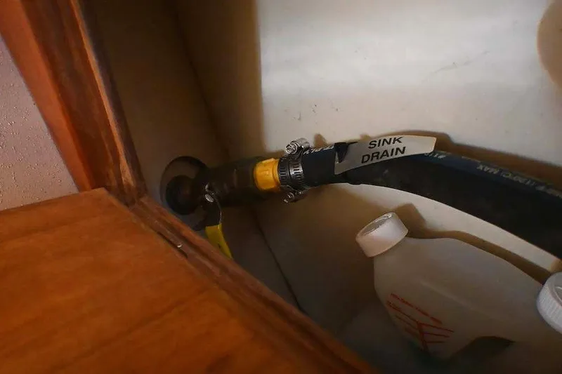Slide: The Image of 2002 Island Packet 350 sink drain hose and container in storage compartment. - 48