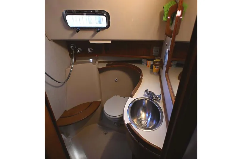 Slide: The Image of 2002 Island Packet 350 yacht bathroom with sink, toilet, and porthole window. - 46