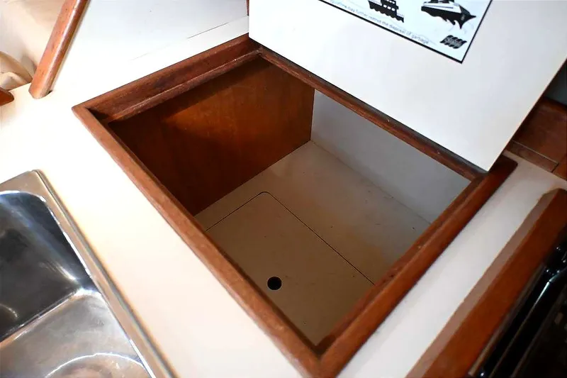 Slide: The Image of Open storage compartment on 2002 Island Packet 350 sailboat, featuring wooden trim and adjacent sink. - 56