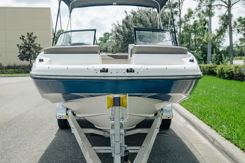 Slide: The Image of 2019 Bayliner 215 Deck Boat on trailer, parked on a sunny day. - 2