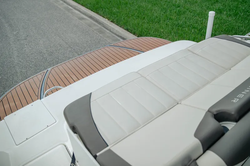 Slide: The Image of 2019 Bayliner 215 Deck Boat with cushioned seating and wooden deck detail. - 10