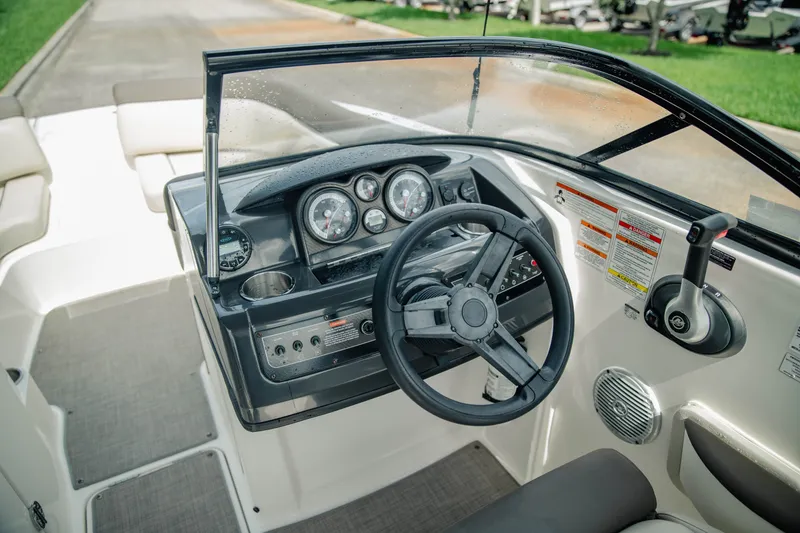 Slide: The Image of 2019 Bayliner 215 Deck Boat cockpit with steering wheel and control panel. - 13