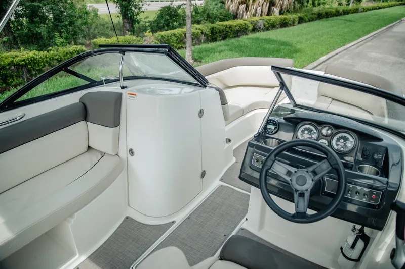 Slide: The Image of 2019 Bayliner 215 Deck Boat interior with steering wheel, seating, and dashboard controls. - 12