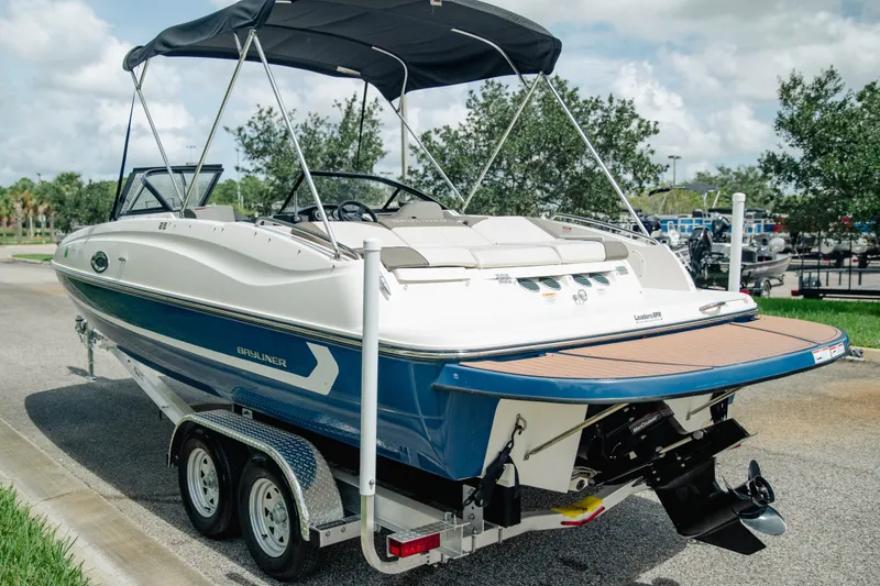 Slide: The Image of 2019 Bayliner 215 Deck Boat on trailer, featuring sleek design and bimini top. - 5