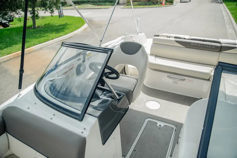 Slide: The Image of 2019 Bayliner 215 Deck Boat interior with steering wheel and seating area. - 15