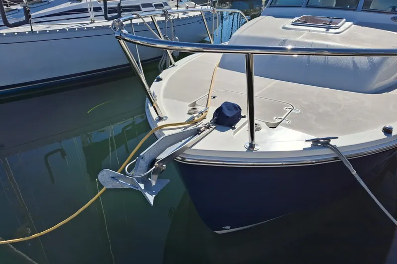 Slide: The Image of 2005 Back Cove 26 boat anchored at marina, featuring sleek bow design and stainless steel railings. - 9