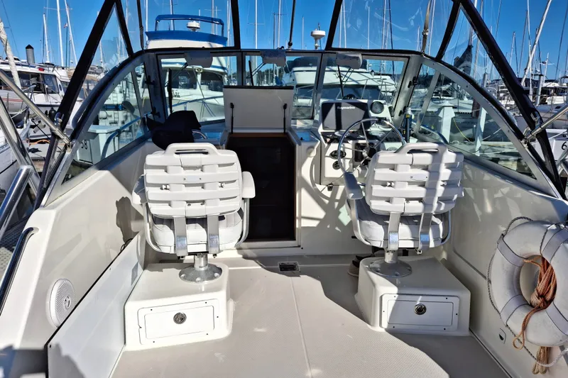 Slide: The Image of 2005 Back Cove 26 boat interior with helm, seating, and marina view. - 5