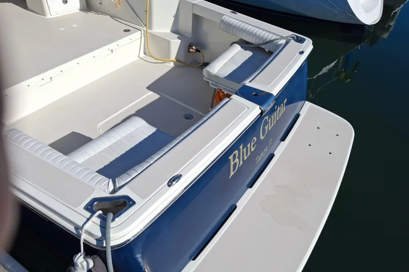 Slide: The Image of 2005 Back Cove 26 boat with "Blue Guitar" name, docked with cushioned seating. - 12