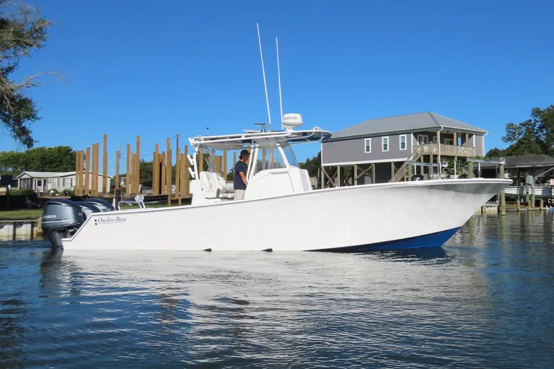 Slide: The Image of 2018 Onslow Bay 33 Tournament Edition boat on calm water near dockside homes. - 11