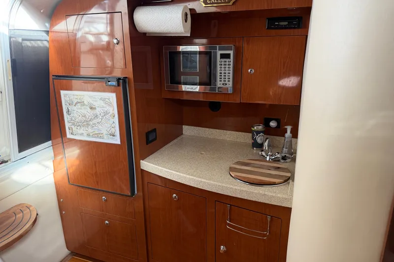 Slide: The Image of 2005 Regal Commodore 3560 yacht kitchen with wood cabinetry, microwave, and countertop sink. - 22