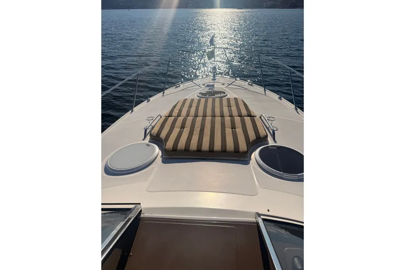 Slide: The Image of Bow view of 2005 Regal Commodore 3560 yacht with striped sun pad on calm water. - 50