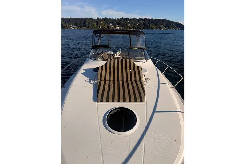 Slide: The Image of 2005 Regal Commodore 3560 yacht on serene lake with sun pad and clear sky. - 51