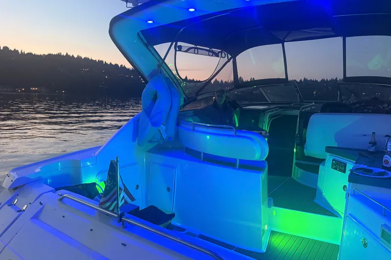 Slide: The Image of 2005 Regal Commodore 3560 yacht with vibrant blue and green LED lights at sunset. - 47