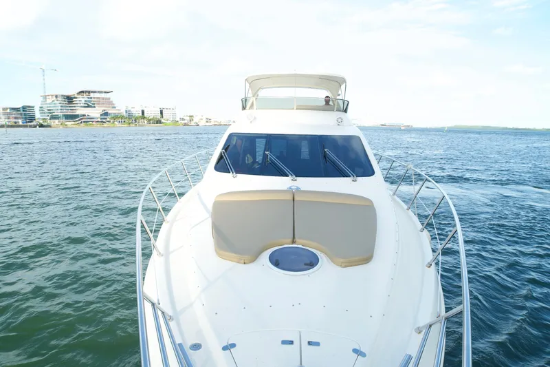 Slide: The Image of 2007 Azimut 55E yacht cruising on open water with modern buildings in the background. - 25