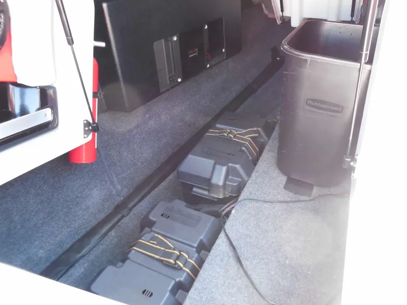 Slide: The Image of View of a 2023 MasterCraft XStar S storage area with batteries and a fire extinguisher. - 27