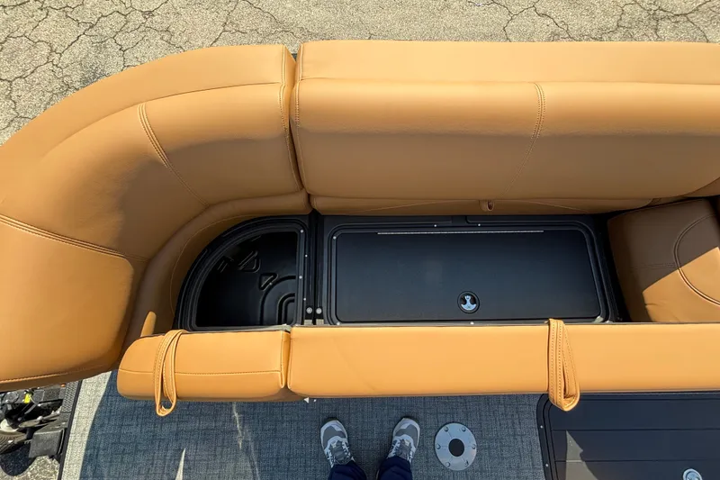 Slide: The Image of Top view of 2027 Regency 230 DL3 boat's tan leather seating and storage compartment. - 7