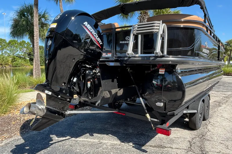 Slide: The Image of 2027 Regency 230 DL3 pontoon boat with Mercury outboard motor, parked on a trailer. - 1