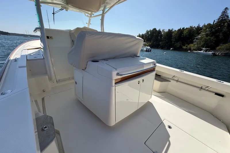 Slide: The Image of 2018 Hunt 32cc boat interior with seating and storage, docked on a sunny day. - 19