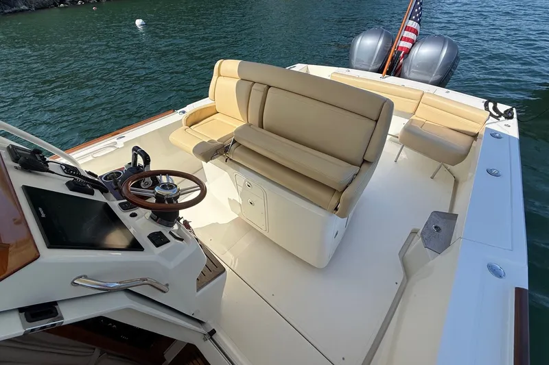 Slide: The Image of 2018 Hunt 32cc boat with beige seating and dual engines on a calm lake. - 11