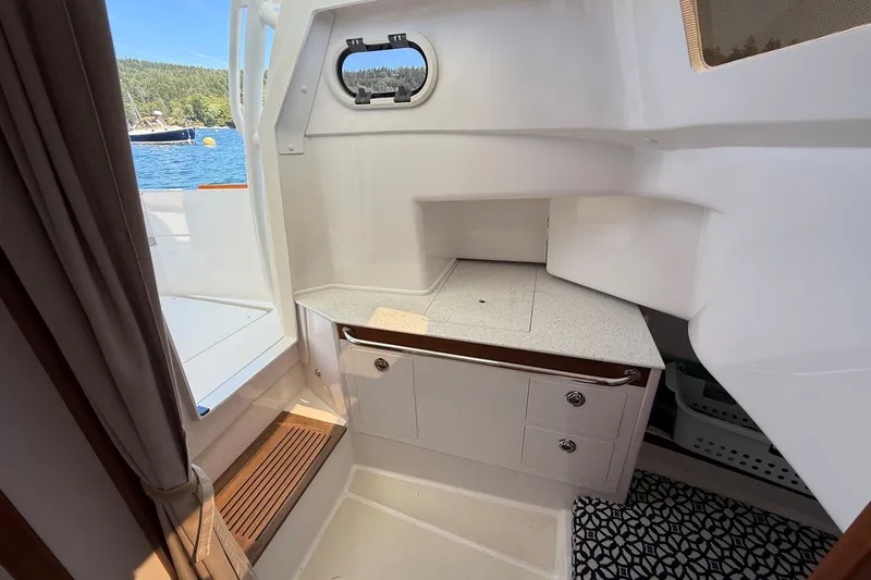 Slide: The Image of Interior view of a 2018 Hunt 32cc boat with a compact kitchenette and scenic water view. - 40