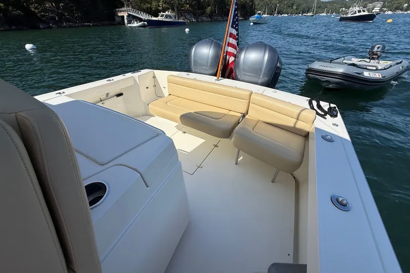 Slide: The Image of 2018 Hunt 32cc boat interior with beige seating, dual engines, and American flag on a sunny day. - 17