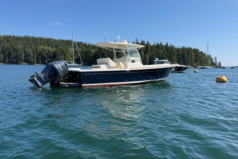 Slide: The Image of 2018 Hunt 32cc boat on water, surrounded by forested shoreline and buoys. - 3