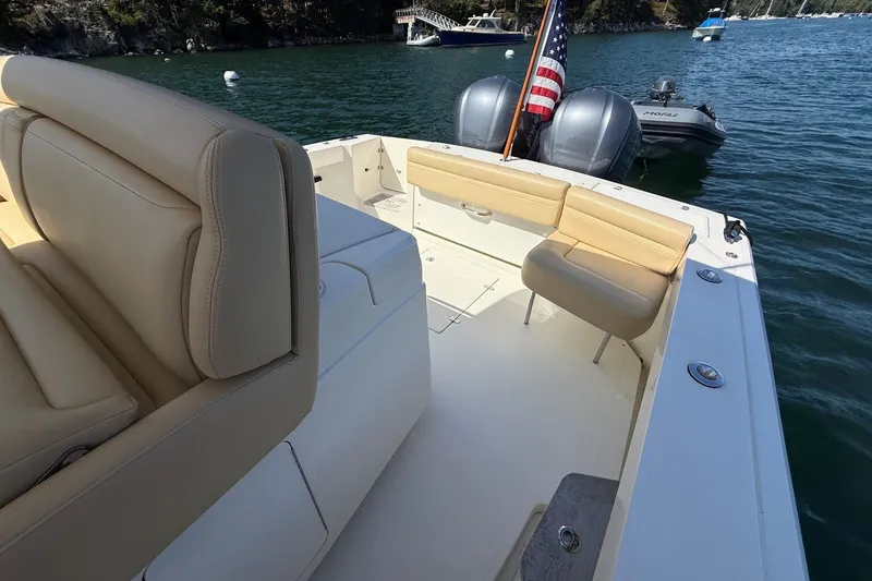 Slide: The Image of 2018 Hunt 32cc boat interior with beige seating, dual engines, and American flag on water. - 15