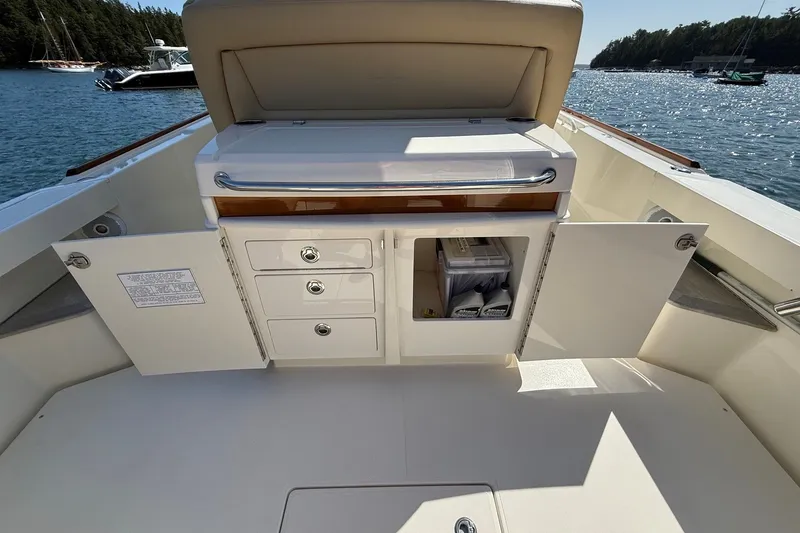 Slide: The Image of 2018 Hunt 32cc boat interior with open storage compartments on a sunny day. - 22