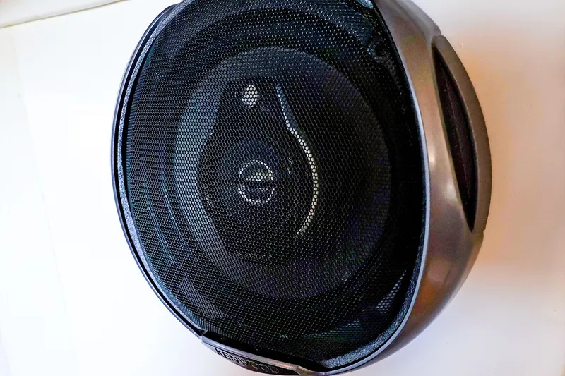 Slide: The Image of A Kenwood car speaker with a black mesh grille, mounted on a white surface. - 36