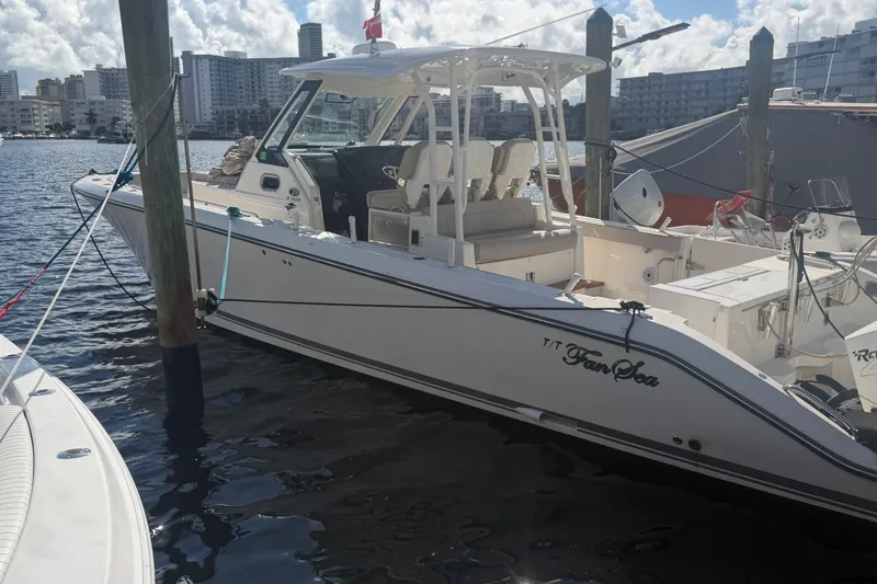 The Image of 2018 Pursuit S 368 Sport boat docked in a marina with cityscape background. - 1