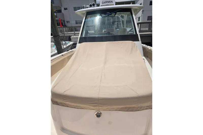 Slide: The Image of 2018 Pursuit S 368 Sport boat with beige cover, docked near buildings. - 12