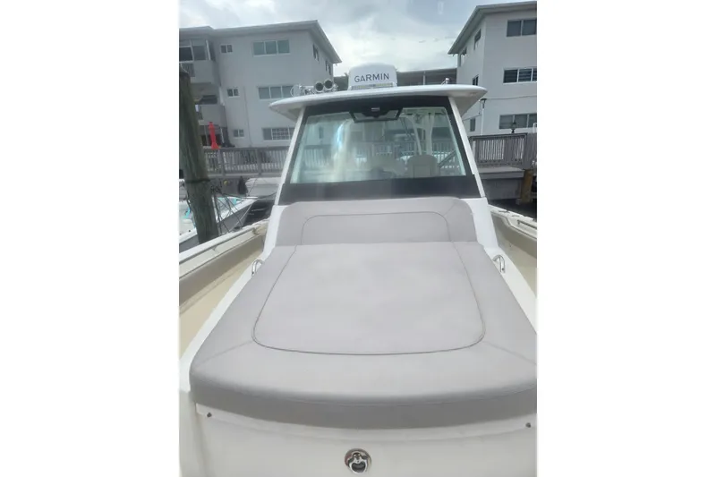 Slide: The Image of 2018 Pursuit S 368 Sport boat with cushioned deck, docked near waterfront buildings. - 24