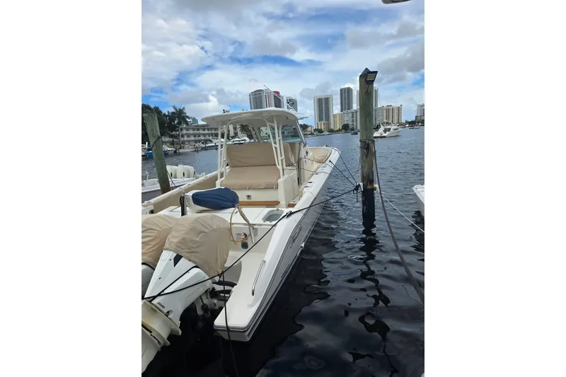 The Image of 2018 Pursuit S 368 Sport boat docked in a marina with city skyline. - 18