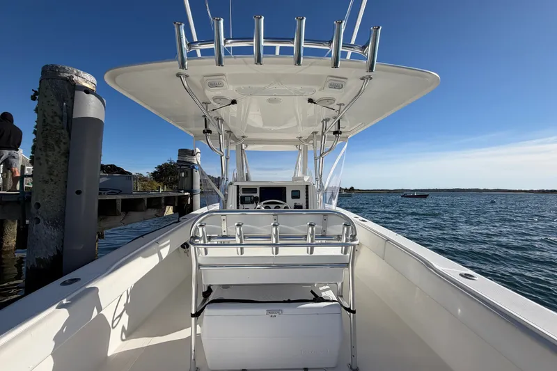 Slide: The Image of 2003 Venture 34 Open boat docked, showcasing helm and seating, with ocean backdrop. - 9