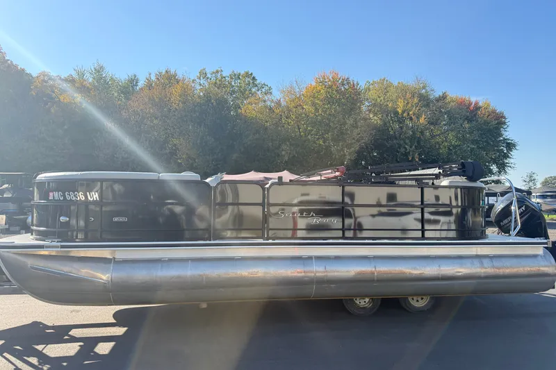 Slide: The Image of 2019 South Bay 224E pontoon boat on trailer, parked outdoors with trees in background. - 5