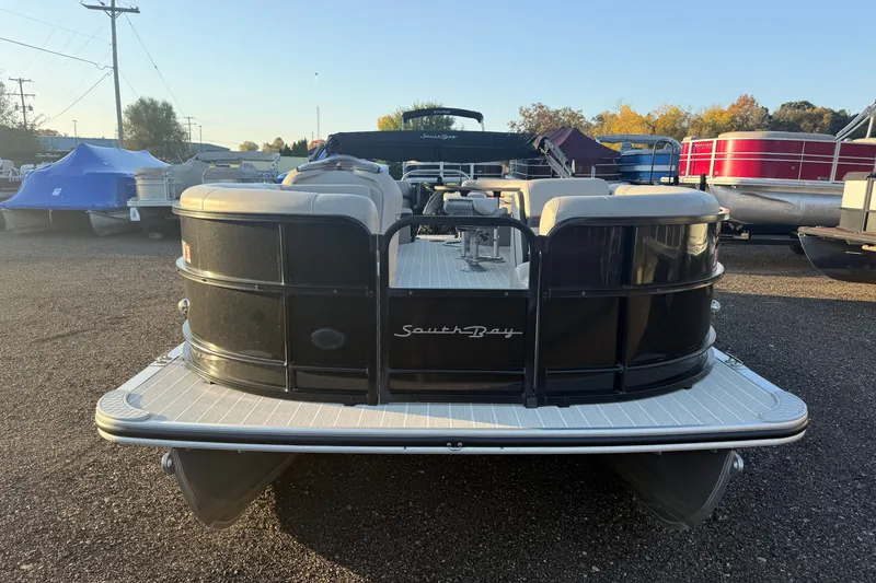 Slide: The Image of 2019 South Bay 224E pontoon boat, black exterior, parked in a marina lot. - 2