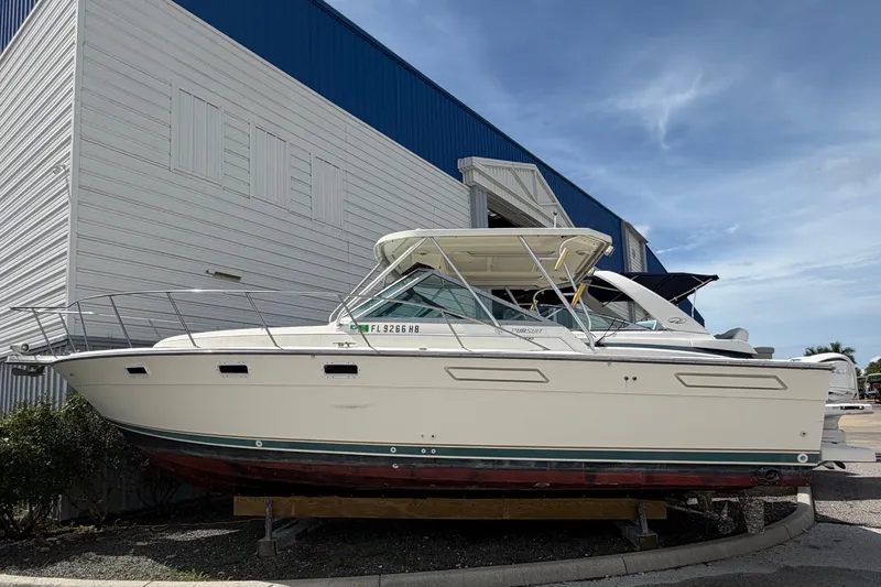 The Image of A 1996 Pursuit 3100 Offshore is on a trailer in front of a building. - 0