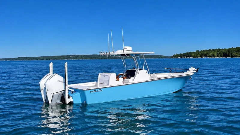 Slide: The Image of A 2025 Valhalla V-29 Hybrid on calm water. The boat has a blue hull and twin outboard engines. - 1