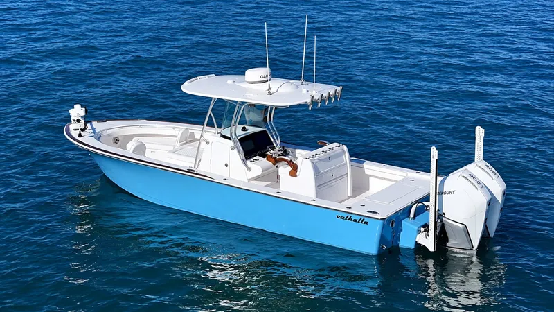Slide: The Image of A 2025 Valhalla V-29 Hybrid on calm water. It features a blue hull and twin outboard engines. - 7